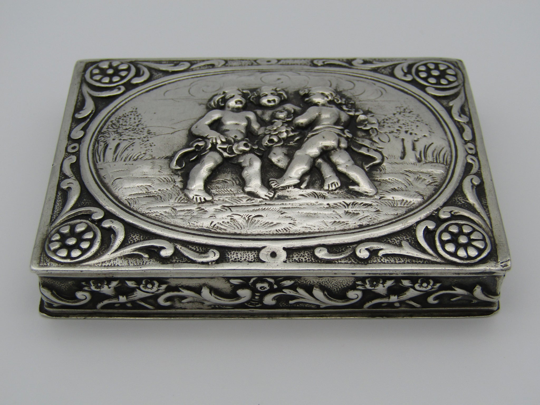 Continental silver table snuff box, stamped 800. The lid is embossed with scrolls and cherubs.